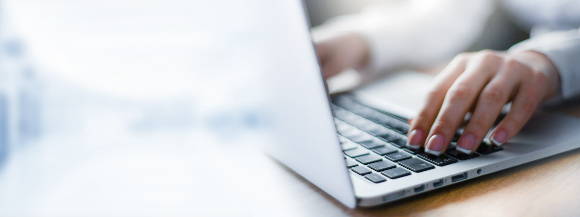 Business woman working on modern computer banner or panorama. Person buying online at internet. Laptop focused on keyboard detail with blur hand. copy space for text.